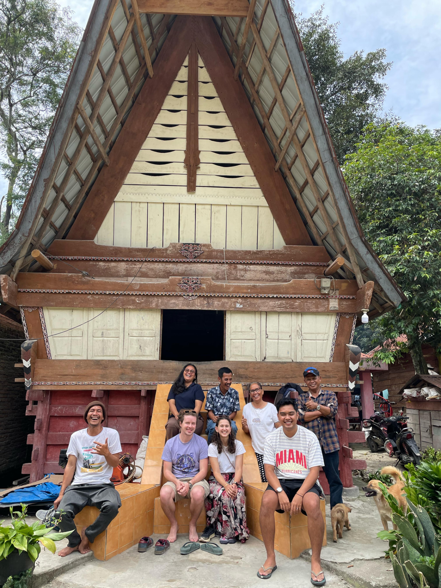 Guests and locals in front of a traditional Batak house
